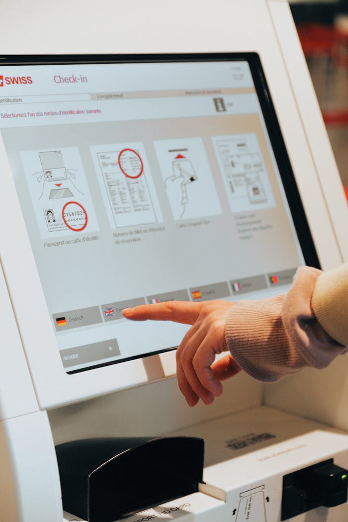 services-01 Hand interacting with airport self-service kiosk for check-in.